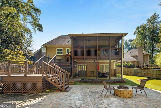 back of house featuring a sunroom, a wooden deck, a patio, and a fire pit