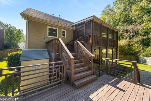 wooden deck with a shed and a sunroom