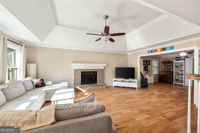 living room featuring wood-type flooring, a fireplace, ornamental molding, and ceiling fan