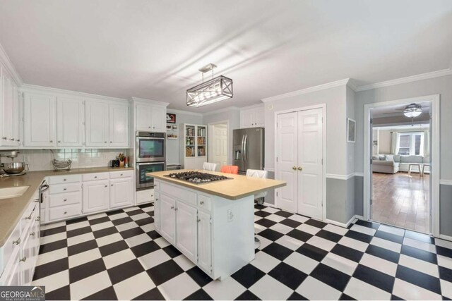 kitchen featuring pendant lighting, a kitchen island, stainless steel appliances, backsplash, and white cabinets