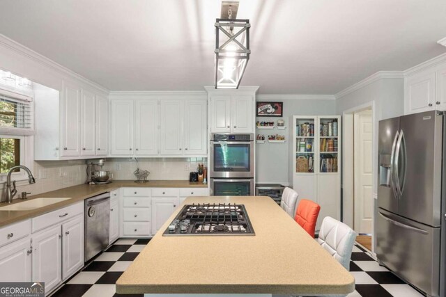 kitchen featuring white cabinets, ornamental molding, stainless steel appliances, and sink