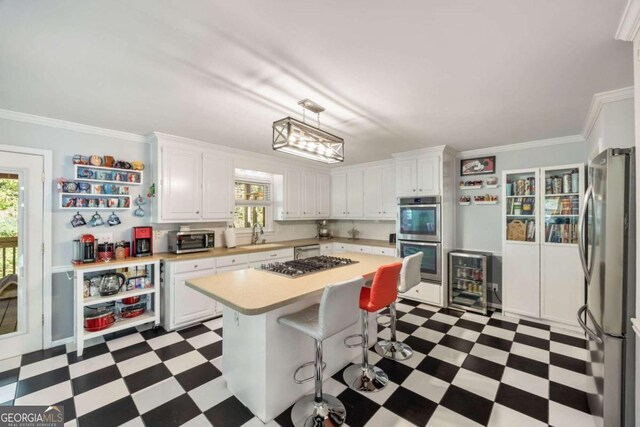 kitchen with appliances with stainless steel finishes, a kitchen island, a wealth of natural light, and white cabinets