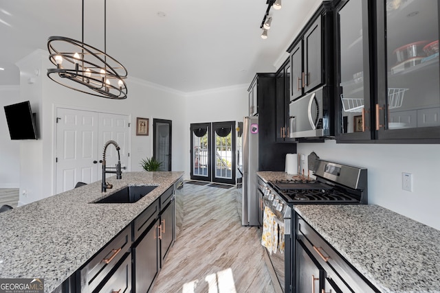 kitchen with hanging light fixtures, ornamental molding, sink, appliances with stainless steel finishes, and light stone counters