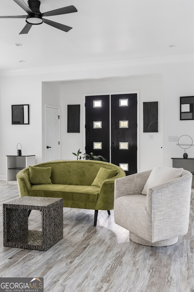 living room with crown molding, light wood-type flooring, and ceiling fan