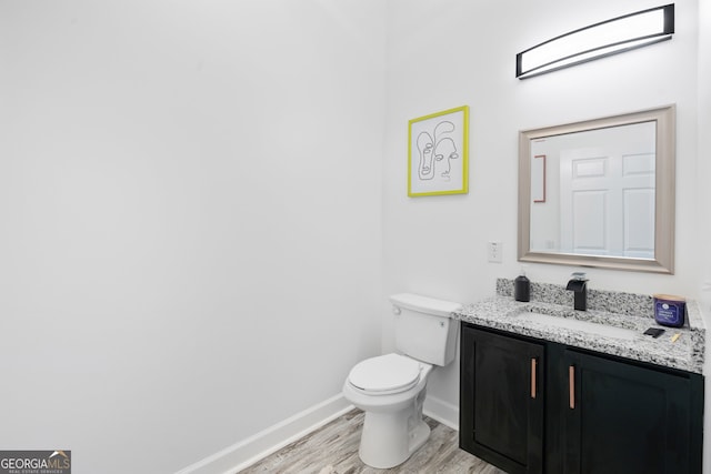 bathroom with toilet, hardwood / wood-style flooring, and vanity