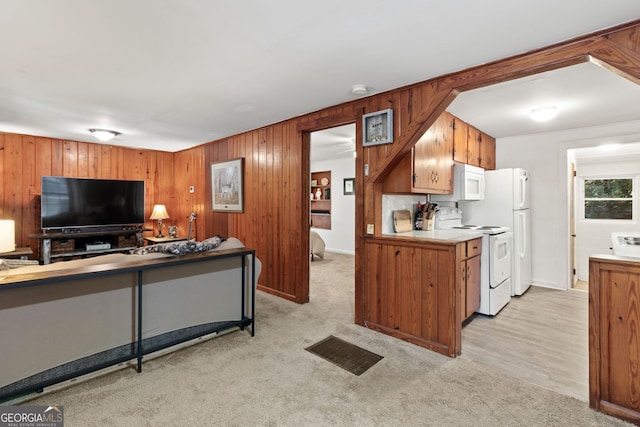 kitchen with light carpet, wood walls, and white appliances