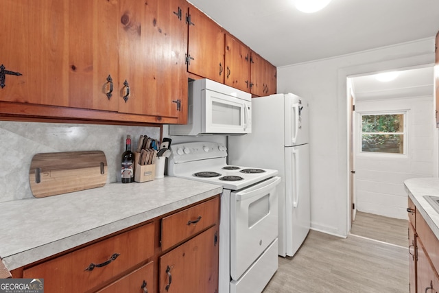 kitchen with white appliances, light hardwood / wood-style floors, and tasteful backsplash