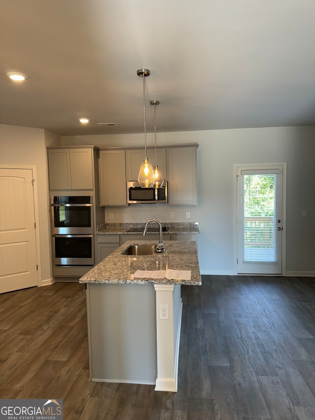 kitchen featuring pendant lighting, dark wood-type flooring, sink, and stainless steel appliances