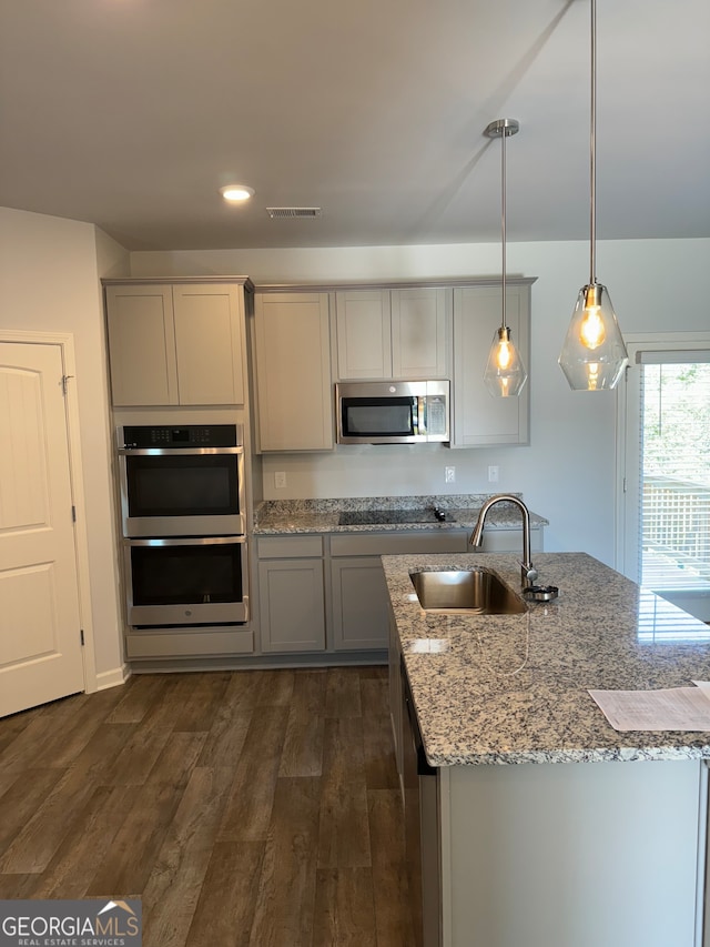 kitchen featuring hanging light fixtures, sink, gray cabinetry, appliances with stainless steel finishes, and dark hardwood / wood-style floors