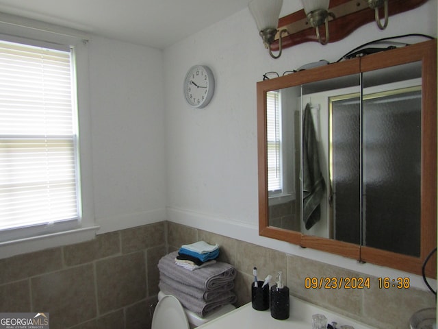 bathroom with walk in shower, tile walls, and a wealth of natural light