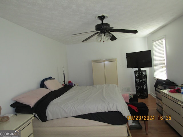 bedroom with ceiling fan, a textured ceiling, and wood-type flooring