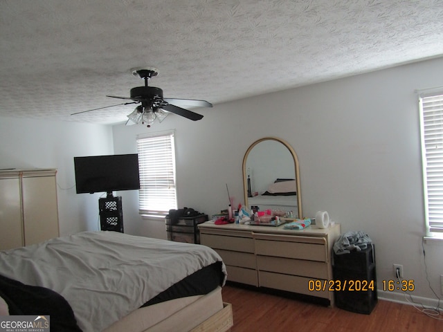 bedroom featuring ceiling fan, hardwood / wood-style flooring, and a textured ceiling