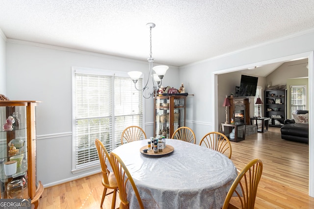 dining room with light hardwood / wood-style flooring, a textured ceiling, vaulted ceiling, and an inviting chandelier