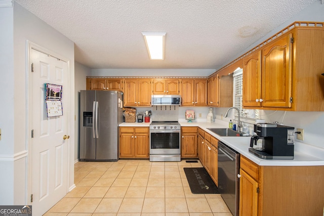 kitchen with appliances with stainless steel finishes, sink, light tile patterned floors, and a textured ceiling