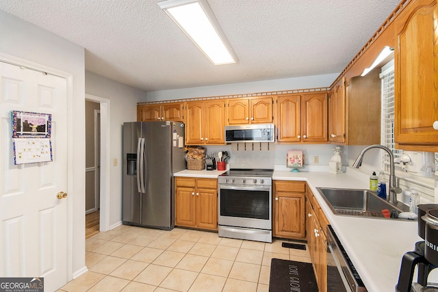 kitchen featuring stainless steel appliances, light tile patterned floors, sink, and a textured ceiling