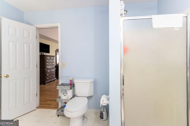 bathroom featuring an enclosed shower, wood-type flooring, a textured ceiling, and toilet