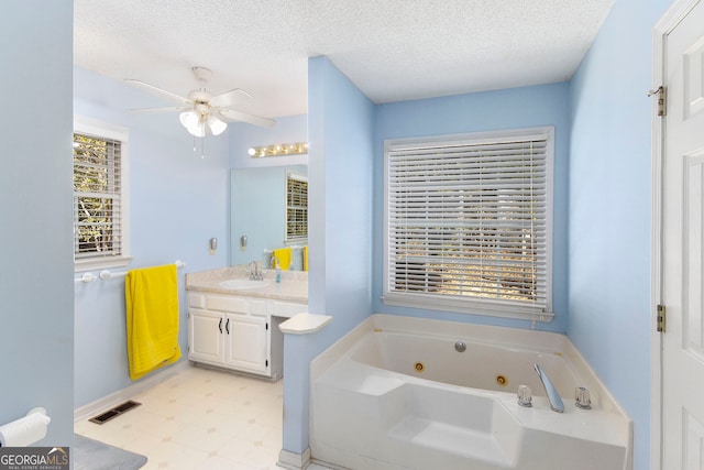 bathroom with a textured ceiling, vanity, a healthy amount of sunlight, and a bath