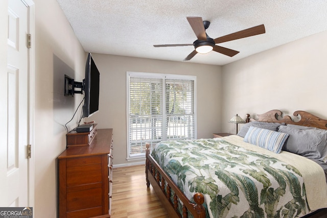 bedroom featuring a textured ceiling, light wood-type flooring, and ceiling fan