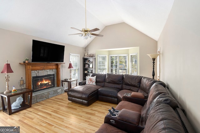 living room with a fireplace, light hardwood / wood-style floors, ceiling fan, and high vaulted ceiling