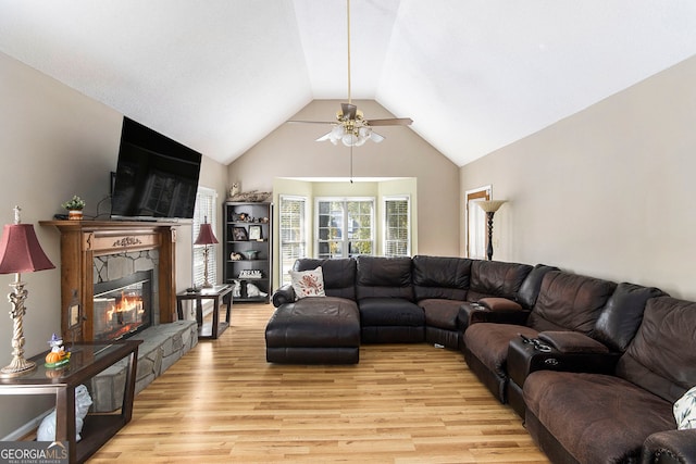 living room featuring ceiling fan, vaulted ceiling, light hardwood / wood-style floors, and a fireplace