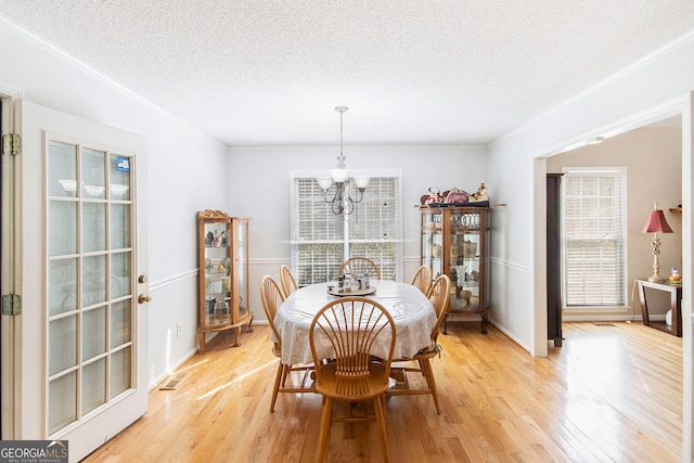 dining space with light hardwood / wood-style floors, a chandelier, and plenty of natural light