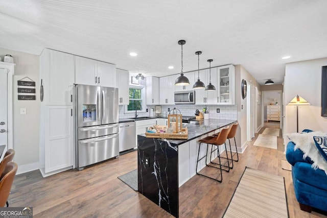 kitchen featuring light wood-type flooring, a kitchen breakfast bar, sink, white cabinets, and appliances with stainless steel finishes