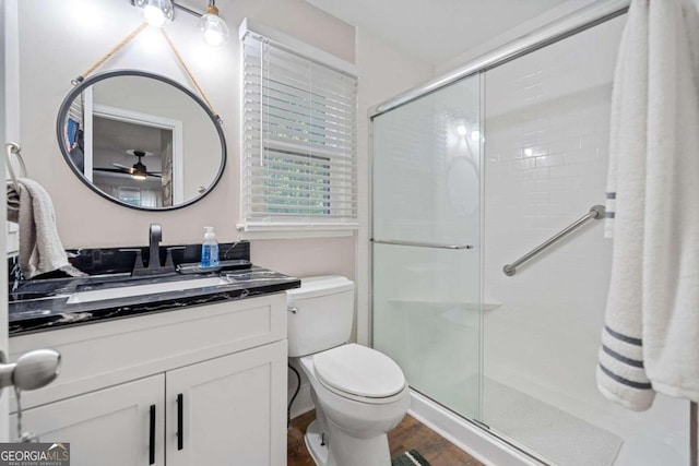 bathroom with ceiling fan, vanity, wood-type flooring, toilet, and a shower with door