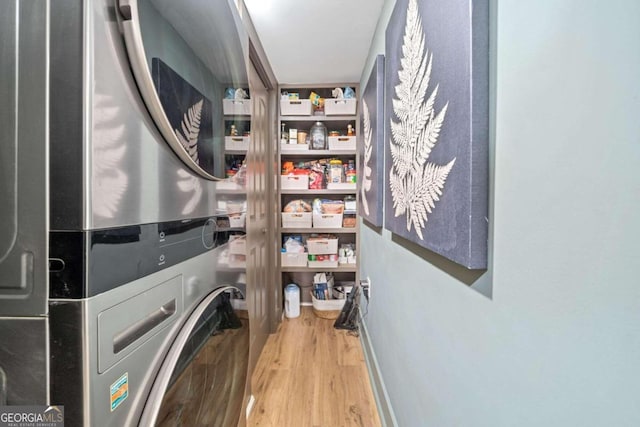 laundry room with stacked washer and dryer and light hardwood / wood-style floors