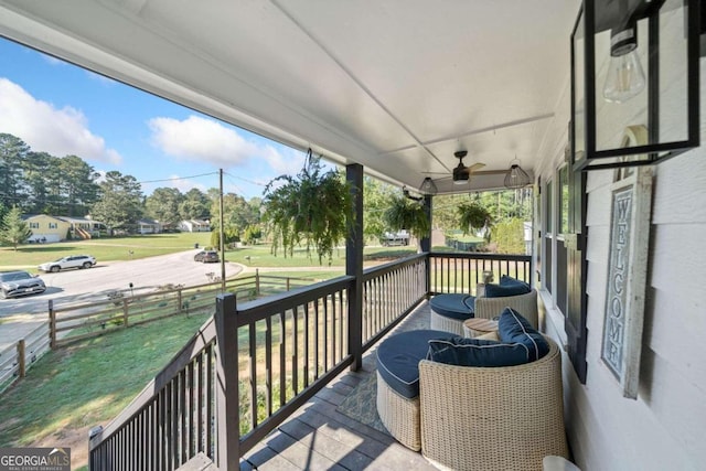 wooden terrace featuring a porch, ceiling fan, and a lawn