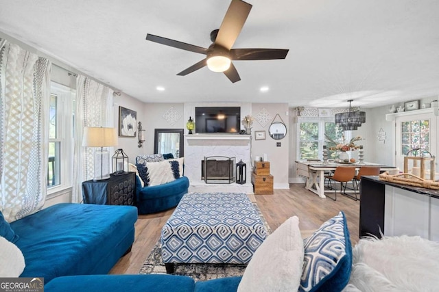 living room with ceiling fan with notable chandelier and light wood-type flooring