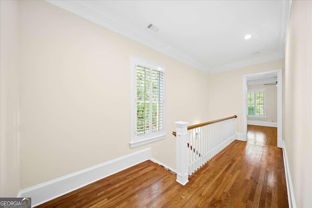 hallway featuring a healthy amount of sunlight, crown molding, and hardwood / wood-style floors