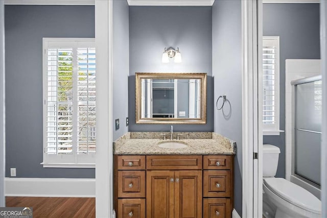 full bathroom with wood-type flooring, vanity, toilet, and combined bath / shower with glass door