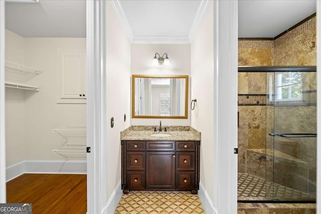 bathroom with vanity, hardwood / wood-style flooring, crown molding, and a shower with door