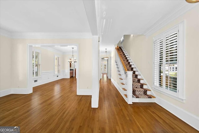 unfurnished living room featuring ornamental molding, a notable chandelier, and dark hardwood / wood-style flooring