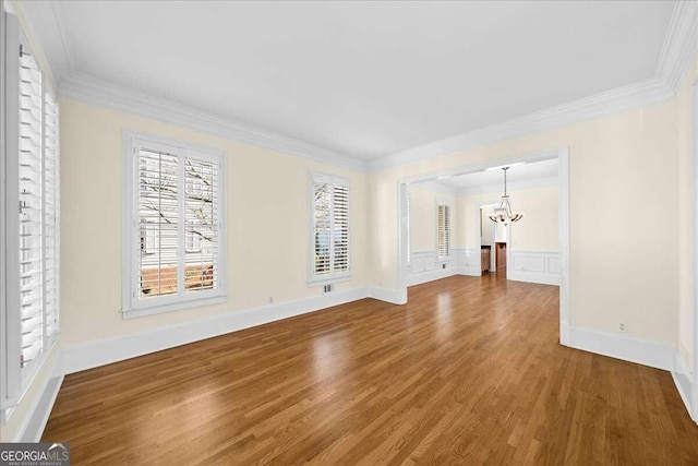 unfurnished living room with hardwood / wood-style flooring, crown molding, and a chandelier