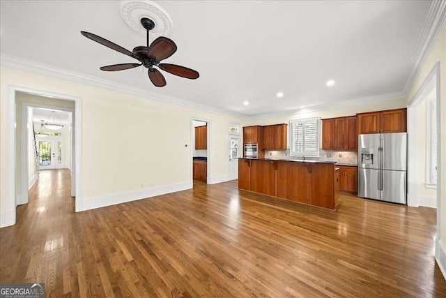 kitchen featuring a kitchen island, ceiling fan, hardwood / wood-style flooring, crown molding, and appliances with stainless steel finishes