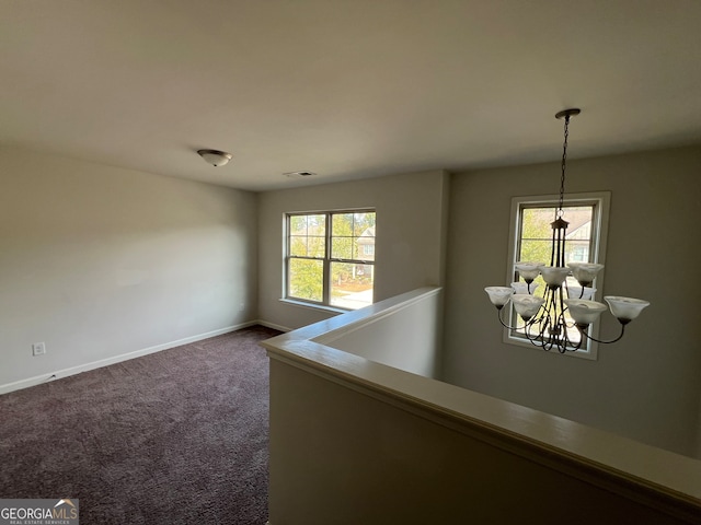 carpeted spare room featuring a notable chandelier