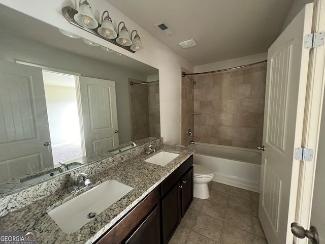 full bathroom featuring tile patterned flooring, vanity, tiled shower / bath combo, and toilet