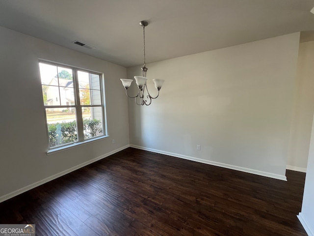 unfurnished dining area featuring dark wood-type flooring and an inviting chandelier