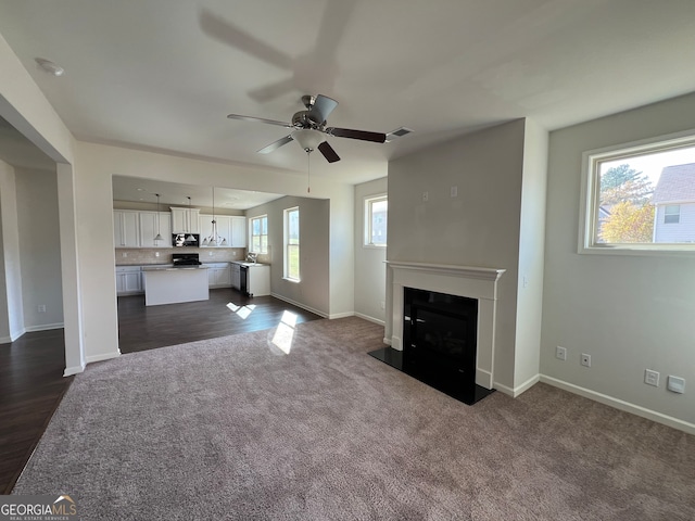 unfurnished living room featuring ceiling fan, sink, and dark hardwood / wood-style floors