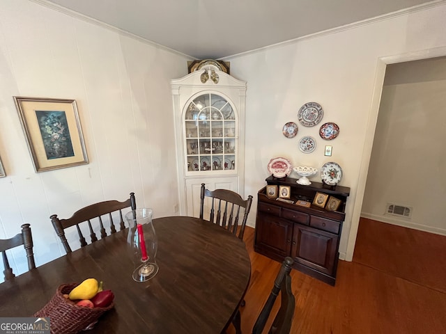 dining area featuring ornamental molding and dark hardwood / wood-style flooring