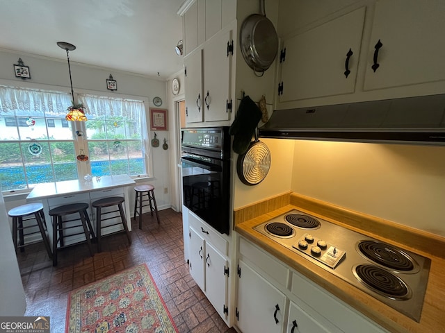 kitchen featuring black oven, white cabinets, decorative light fixtures, and stainless steel electric stovetop