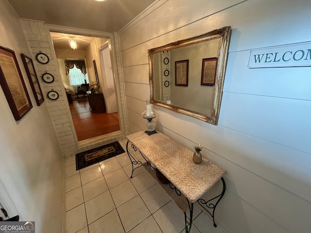 hallway with ornamental molding and light tile patterned floors