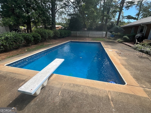 view of pool with a diving board and a patio area