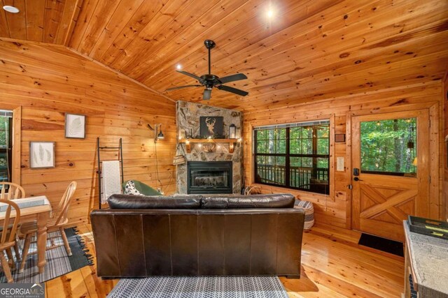 living room with light wood-type flooring, wooden walls, lofted ceiling, and wooden ceiling