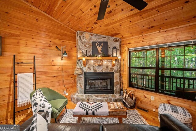 living room featuring hardwood / wood-style floors, wood ceiling, a stone fireplace, vaulted ceiling, and wood walls