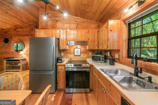 kitchen with wood walls, wood ceiling, vaulted ceiling, sink, and stainless steel appliances