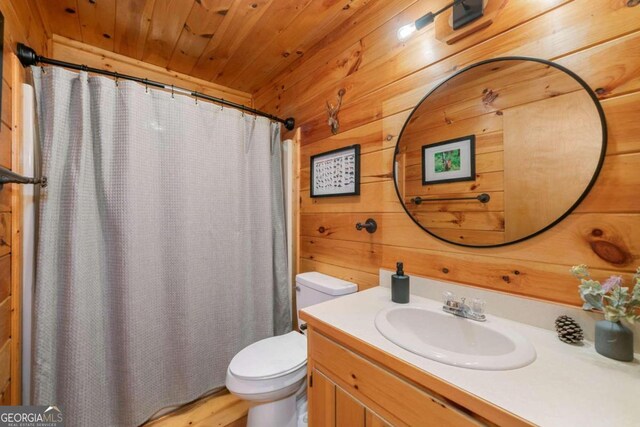 bathroom with vanity, wood walls, toilet, and wooden ceiling