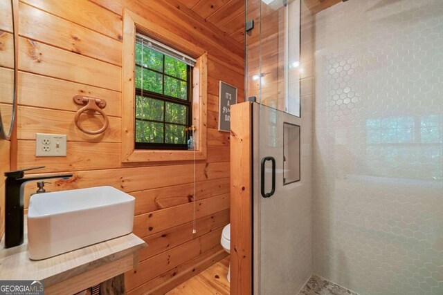 bathroom featuring wood walls, toilet, and a shower with door