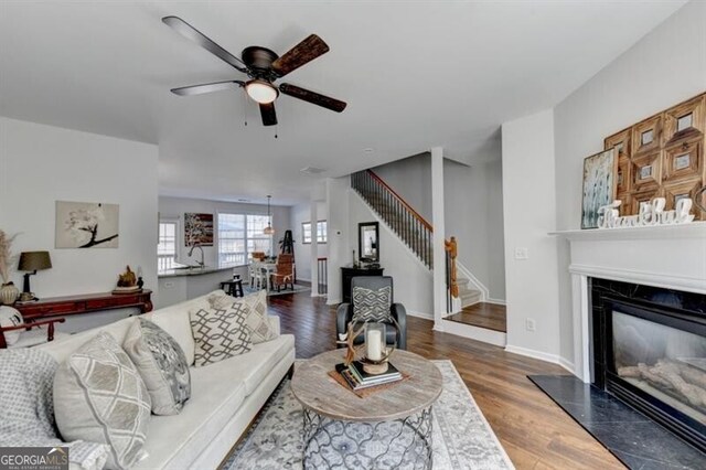 living room featuring dark hardwood / wood-style floors, a high end fireplace, and ceiling fan